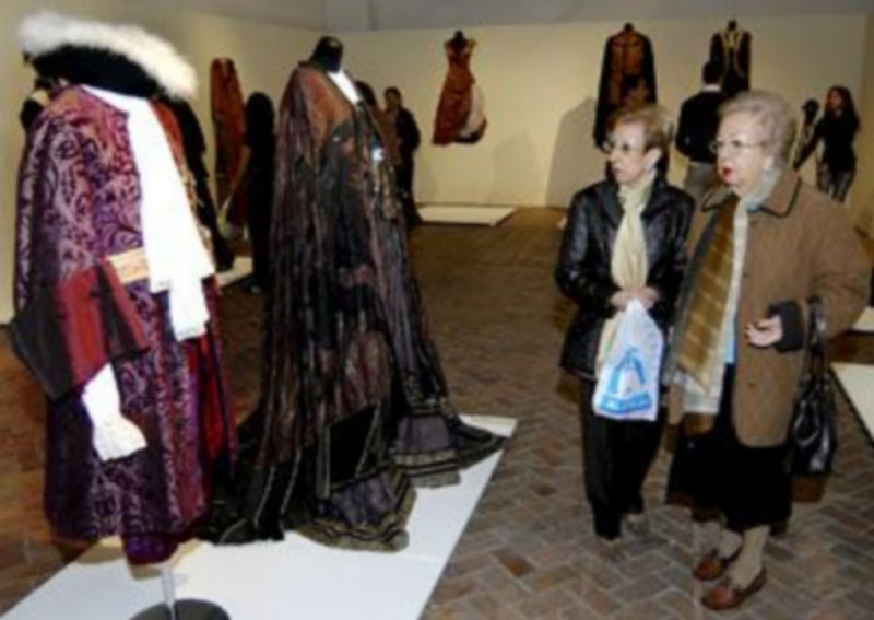 Dos visitantes contemplan algunos de los trajes expuestos en La Alhóndiga