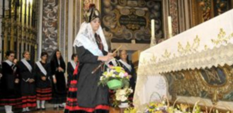 La alcaldesa de las fiestas deposita un centro de flores frente al altar mayor del santuario. / JUAN MARTÍN.