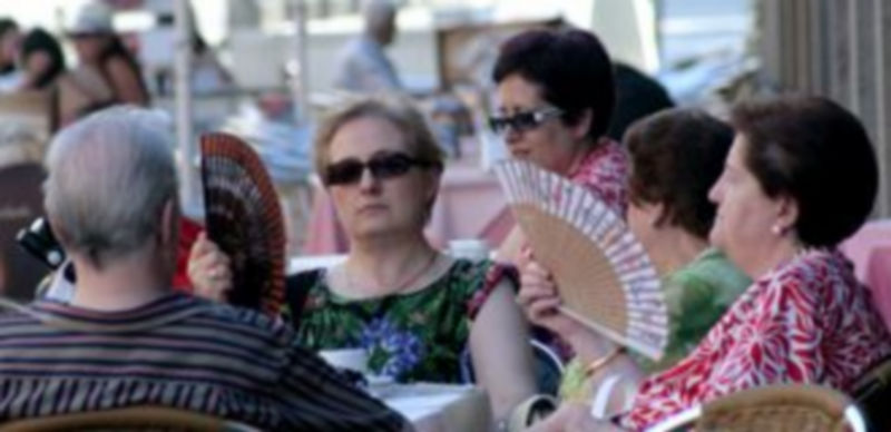 Varias personas intentan aliviarse del calor con abanicos y tomando refrescos en una terraza de la capital. / L. Mazagatos