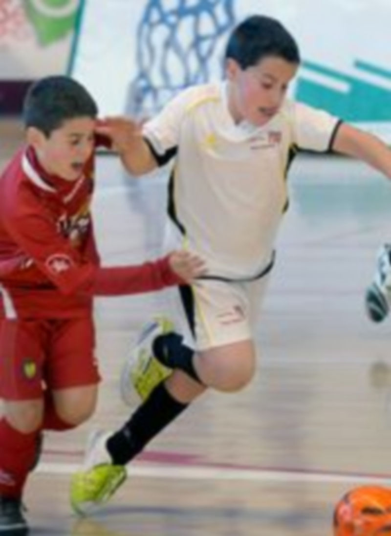 Un jugador alevín del Caja Segovia intenta salir con el balón controlado junto a un rival de ElPozo Murcia. / Alberto Benavente