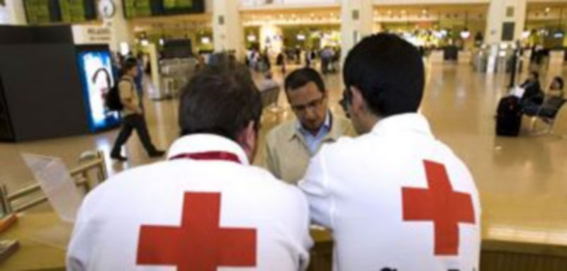 Voluntarios de la Cruz Roja informan a un pasajero sobre la gripe AH1N1 en uno de los tres puntos de información instalados en el aeropuerto de Málaga./ EFE
