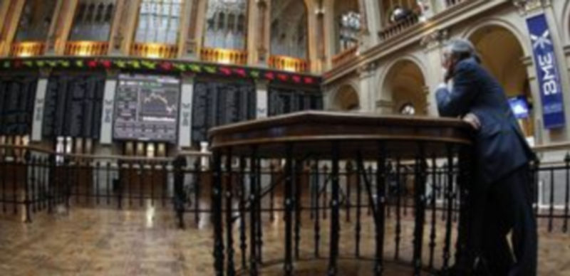 Interior del palacio de la Bolsa española en el que varias personas observan las pantallas de contratación ayer antes del cierre de sesión./ EFE