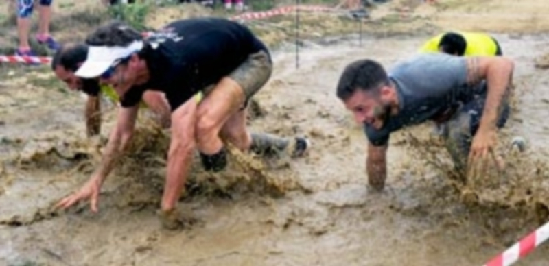 Cuatro participantes cruzan una zona embarrada del circuito de la UVa Running Race en las inmediaciones de Baterías de la Academia de Artillería. / KAMARERO