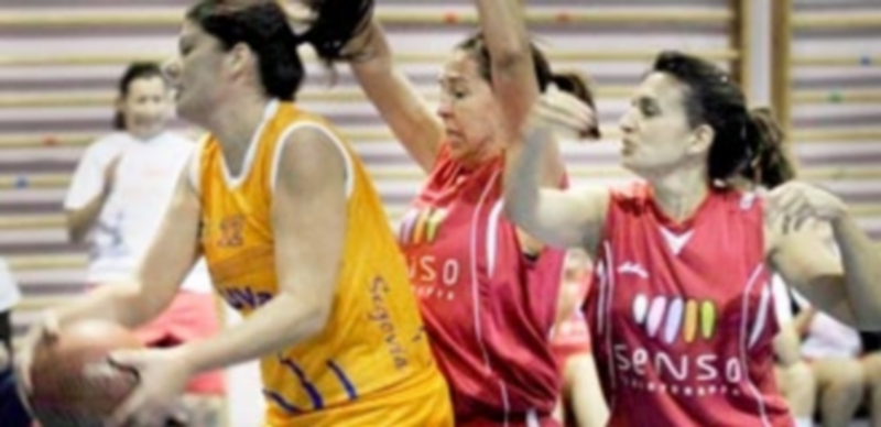 Una jugadora de la UVa Sg recoge un rebote ante la presión de dos componentes del Fisioterapia Senso. / KAMARERO