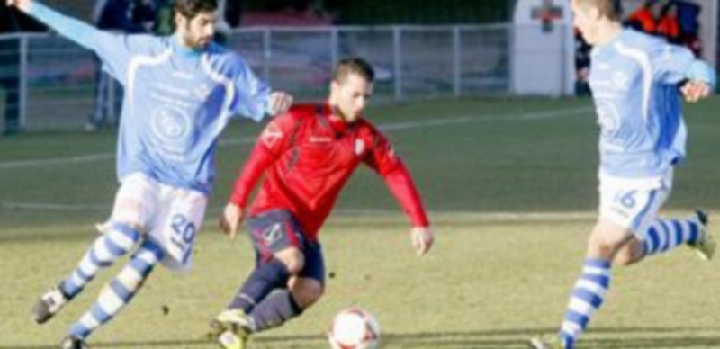 Un jugador abulense controla el balón entre los granjeños Ricardo y Xavi