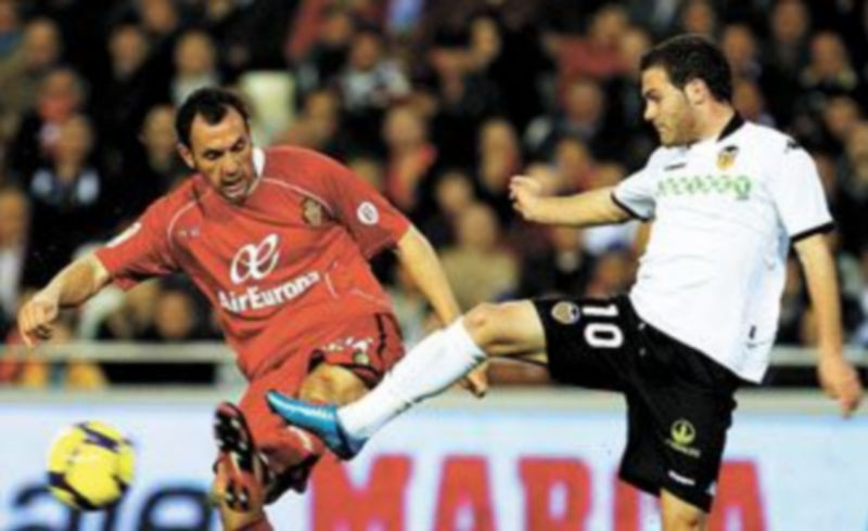 El centrocampista del Valencia Juan Mata (d) disputa un balón con el defensa del Mallorca Iván Ramis. / Efe