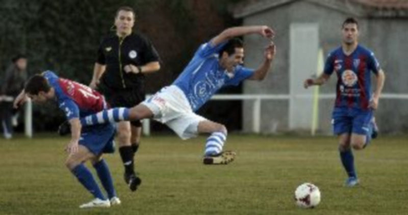 El delantero granjeño César Bravo a punto de caer al césped junto al gimnástico Manu