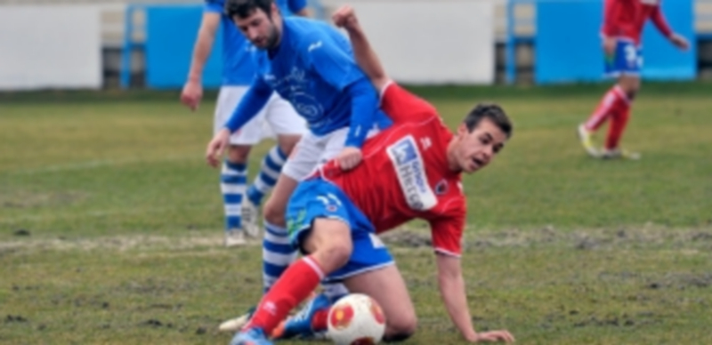 Un jugador del Numancia B consigue hacerse con el balón después de presionar al jugador del CD La Granja