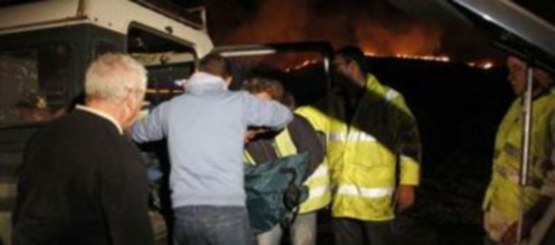 Miembros de los servicios de emergencia introducen en un vehículo el cuerpo sin vida de uno de los dos miembros de una brigada de lucha contra incendios./ EFE