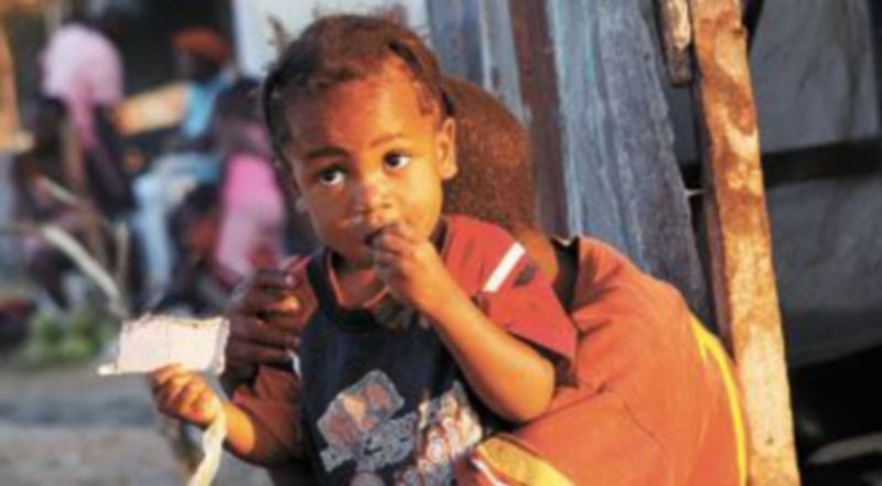 Un niño mastica un trozo de cartón en uno de los campamentos para refugiados habilitados a las afueras de Puerto Príncipe. / SHANNON STAPLETON