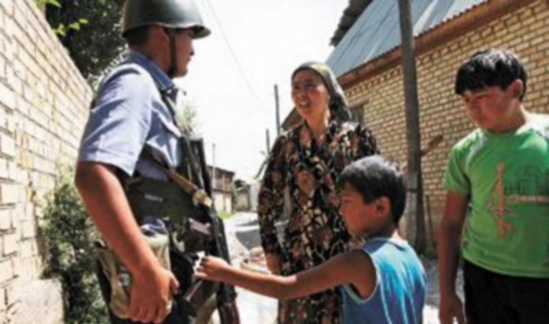 Un niño kirguís muestra su interés por el arma de un soldado que patrulla por la ciudad de Suzak