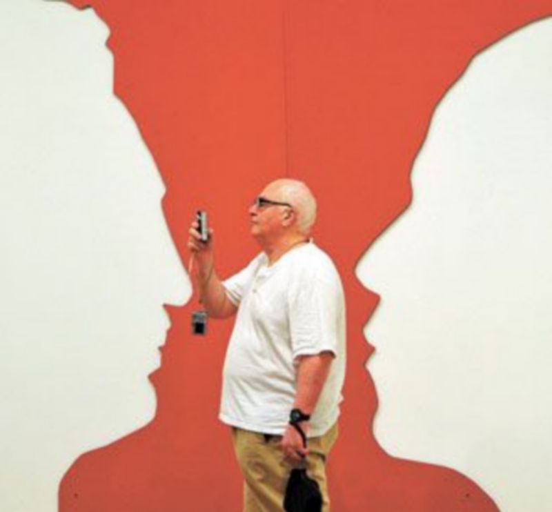 Un hombre toma fotografías junto a una obra con los perfiles de Barack Obama y Fidel Castro. / EFE