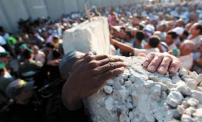 La mano de un policía israelí (i) permanece junto a la de un palestino mientras trata de impedir el acceso a Jerusalén de cisjordanos indocumentados. / Atef Safadi (Efe)