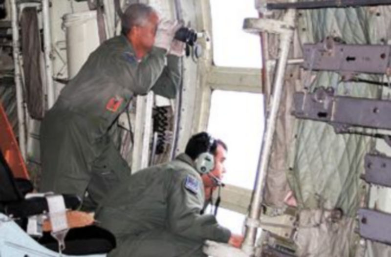 Dos militares brasileños escudriñan las aguas del océano desde un avión de rescate en busca de restos del aparato siniestrado. / EFE