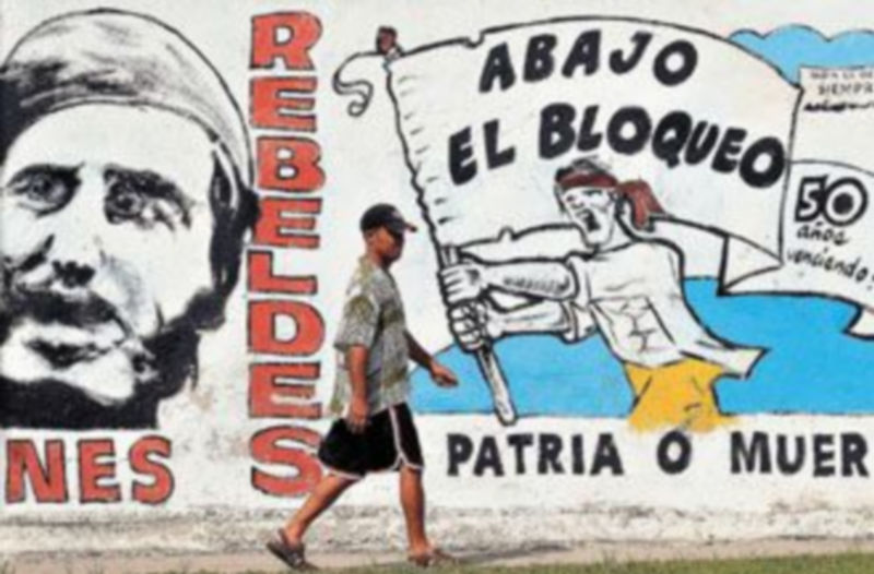 Un hombre camina por una calle de La Habana junto a un mural alusivo a la revolución cubana y al embargo norteamericano. / Alejandro Ernesto (Efe)