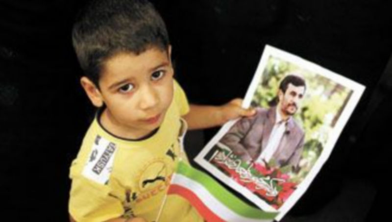 Un niño sostiene un cartel electoral del presidente iraní