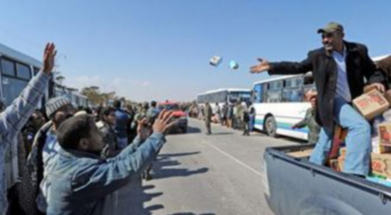 Voluntarios repartes alimentos a los refugiados que hacen cola para cruzar a Túnez por el paso de Ras el Jedir. /EFE