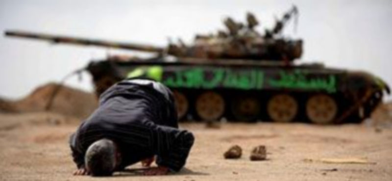 Un insurgente libio reza junto a los restos de un tanque destruído./EFE/MAURIZIO GAMBARINI.