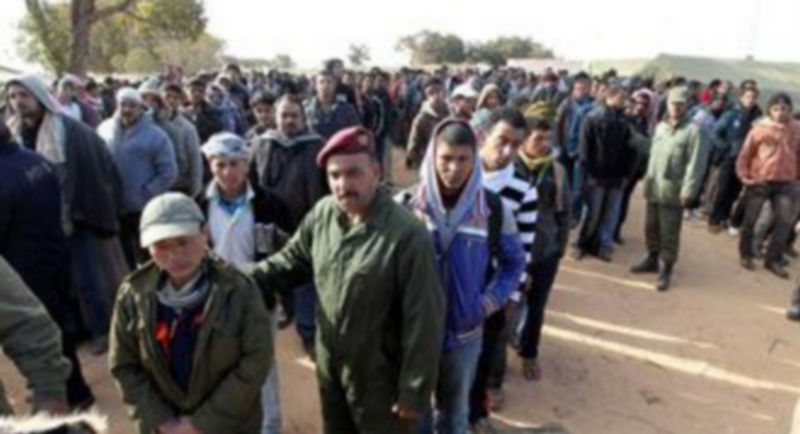 Refugiados egipcios hacen cola para recibir alimentos en un campamento establecido cerca del paso fronterizo de Ras Jdir