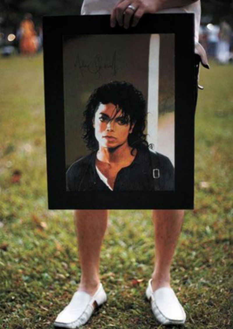 Un seguidor de Michael Jackson en Singapur sostiene un póster con el rostro del artista. / Reuters