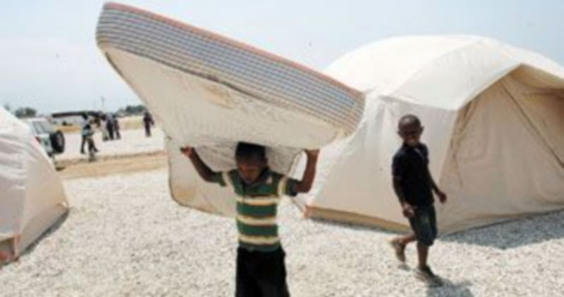 Un niño haitiano carga un colchón en el nuevo asentamiento para desplazados por el terremoto levantado junto a la localidad de Santos. / Efe