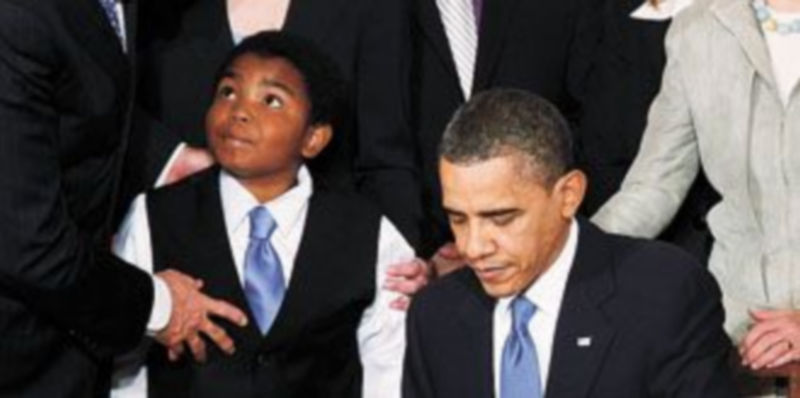 Obama firma la ley junto a Joe Biden y un niño invitado al acto. /Reuters