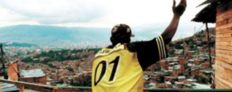 Un pandillero armado saluda desde una comuna de la ciudad colombiana de Medellín. / Efe