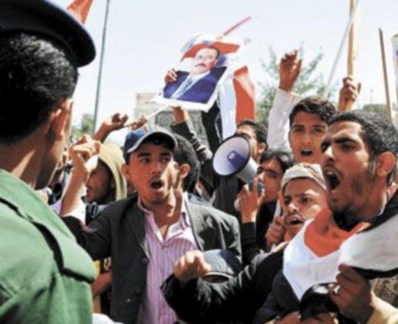 Un soldado vigila a varios simpatizantes del Gobierno a las puertas de la Universidad de Saná