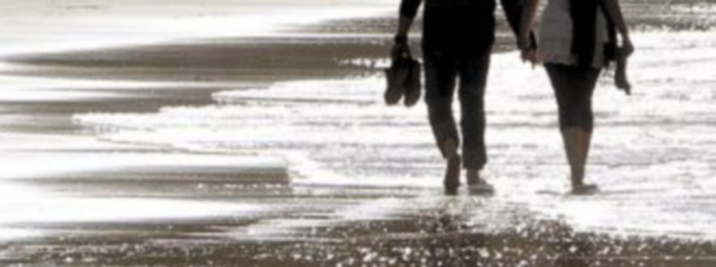 Una pareja camina por la orilla de una playa del norte de la península española