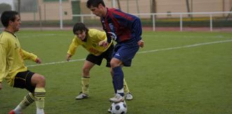 Dos jugadores del Quintanar observan a un rival de la Gimnástica Segoviana que pisa el balón. / Kamarero