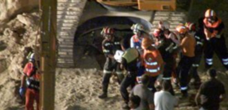 Miembros del cuerpo de bomberos trasladan el cuerpo sin vida de una de las tres personas que habían quedado atrapadas./EFE