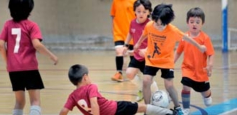 Un joven jugador intenta quitarle un balón a un rival lanzándose al suelo
