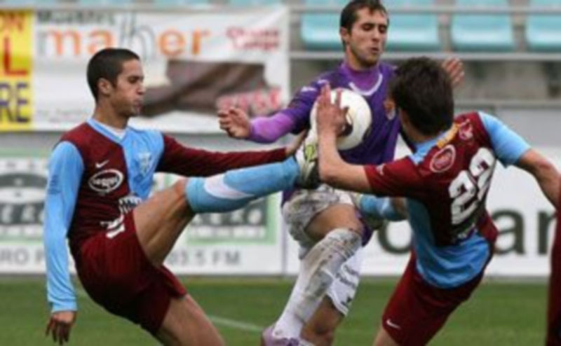 Jesús Alonso y Maikel tratan de hacerse con el balón elevando la pierna ante la oposición del jugador del Palencia. / Óscar Navarro