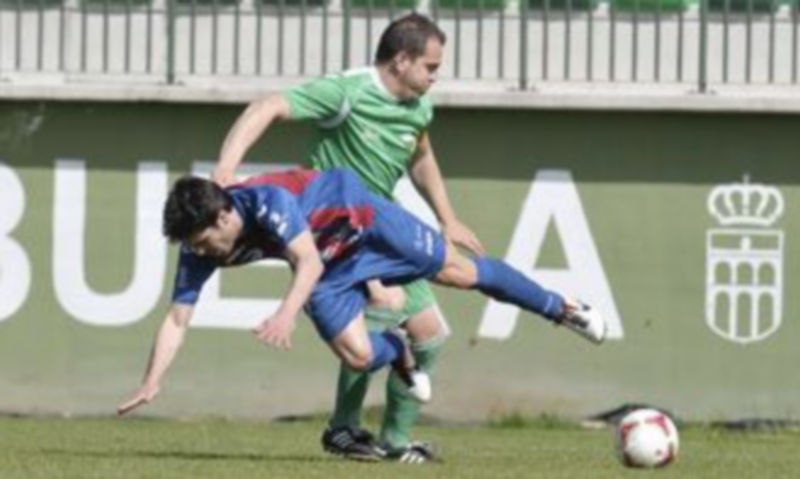 El delantero de la Gimnástica Segoviana a punto de caer al césped tras la fuerte defensa de un rival del Club Deportivo La Virgen del Camino