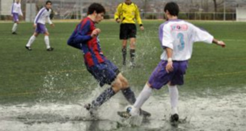 El segoviano Demi y el palentino David Alfonso intentan sacar el balón del gran charco formado sobre el terreno de juego. / J.M.