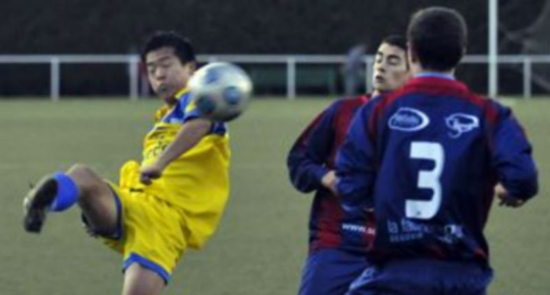 Un jugador de La Amistad golpea el balón ante dos futbolistas de la Gimnástica Segoviana. / Juan Martín