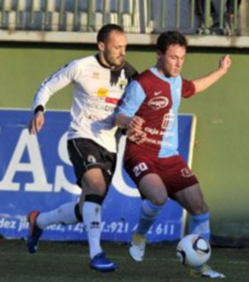 Víctor Pérez recibe la presión de un jugador del Burgos durante un encuentro disputado en La Albuera. / Kamarero