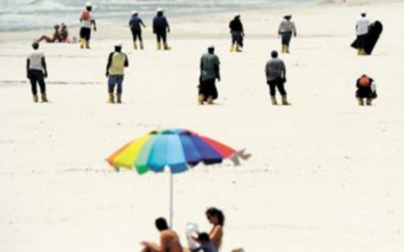 Operarios buscan en la playa restos de chapapote en la isla de Dauphin