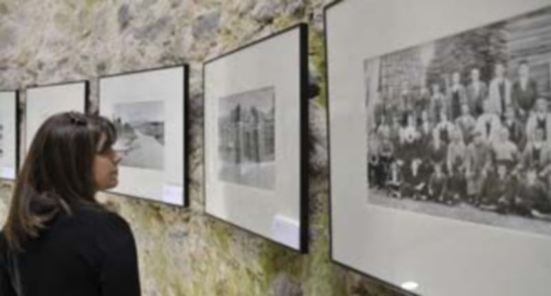 Una vecina del Real Sitio observando las proyecciones fotográficas de la exposición ‘Tiempo de Recuerdos’ ubicada en el espacio cultural El Pozo de la Nieve. / Juan Martín