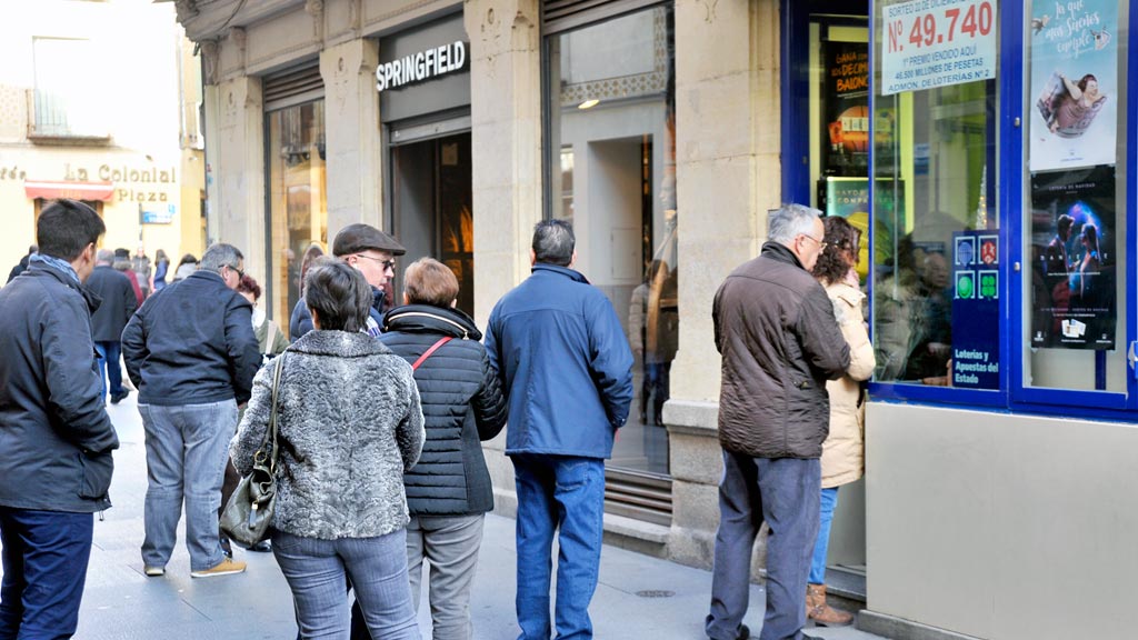 Segovianos y turistas hacen cola estos días en las administraciones segovianas, como ésta de la Calle Real, para comprar los décimos de la suerte. /kamarero