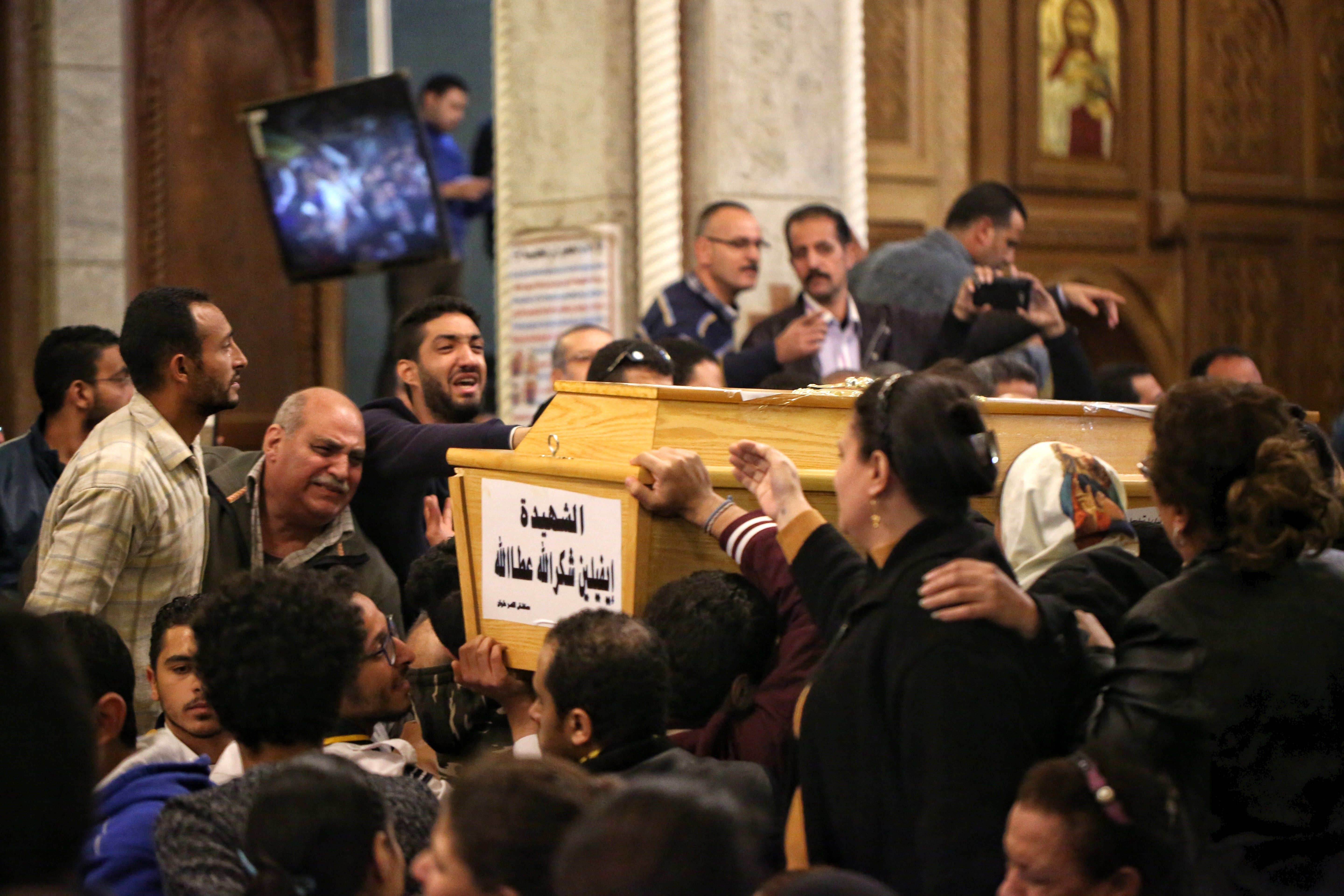 Varias personas rodean el féretro de una mujer víctima del ataque.