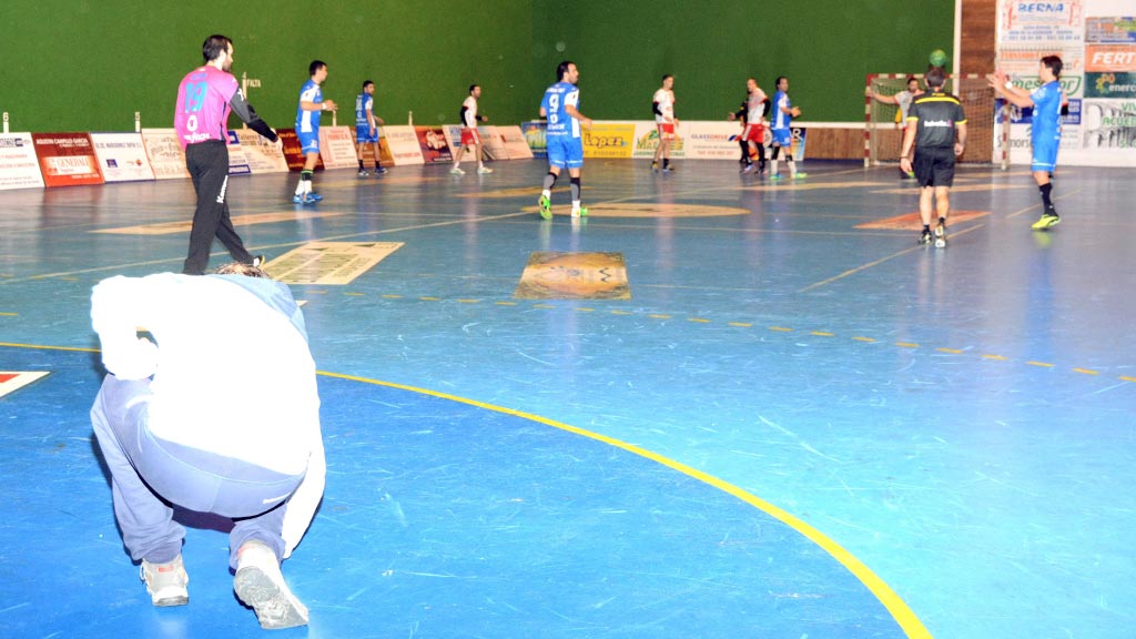 Un directivo del Balonmano Nava seca la pista durante un partido. / A. MARUGÁN