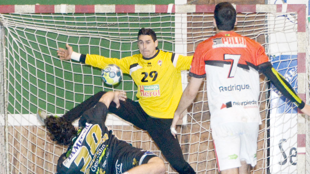 Yeray Lamariano intenta rechazar el lanzamiento del pivote Moreira desde los seis metros en una acción del encuentro jugado en Nava. / AMADOR MARUGÁN