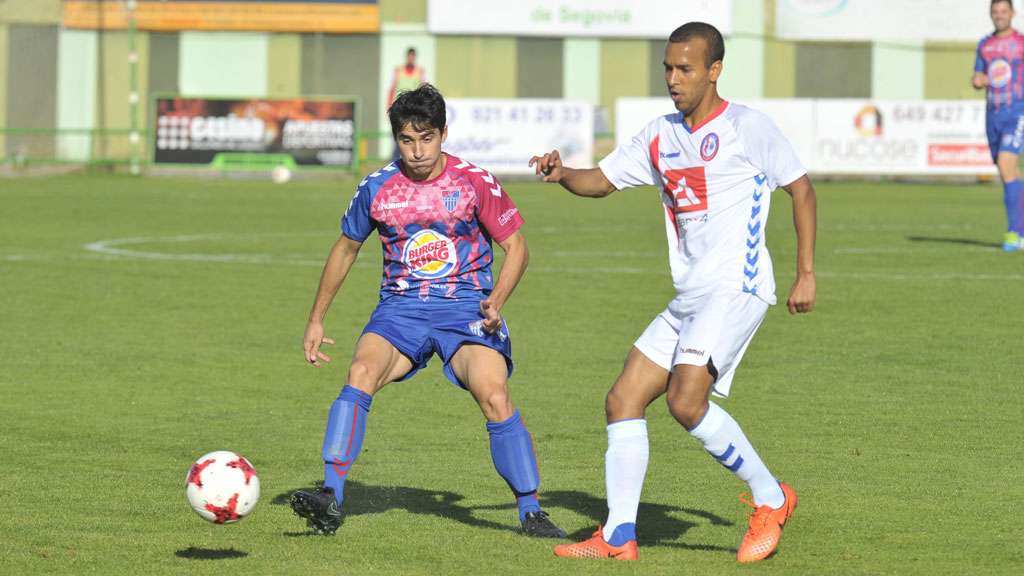 El centrocampista de la Segoviana Quino contiene la posición ante la presión de un rival del Majadahonda. / KAMARERO