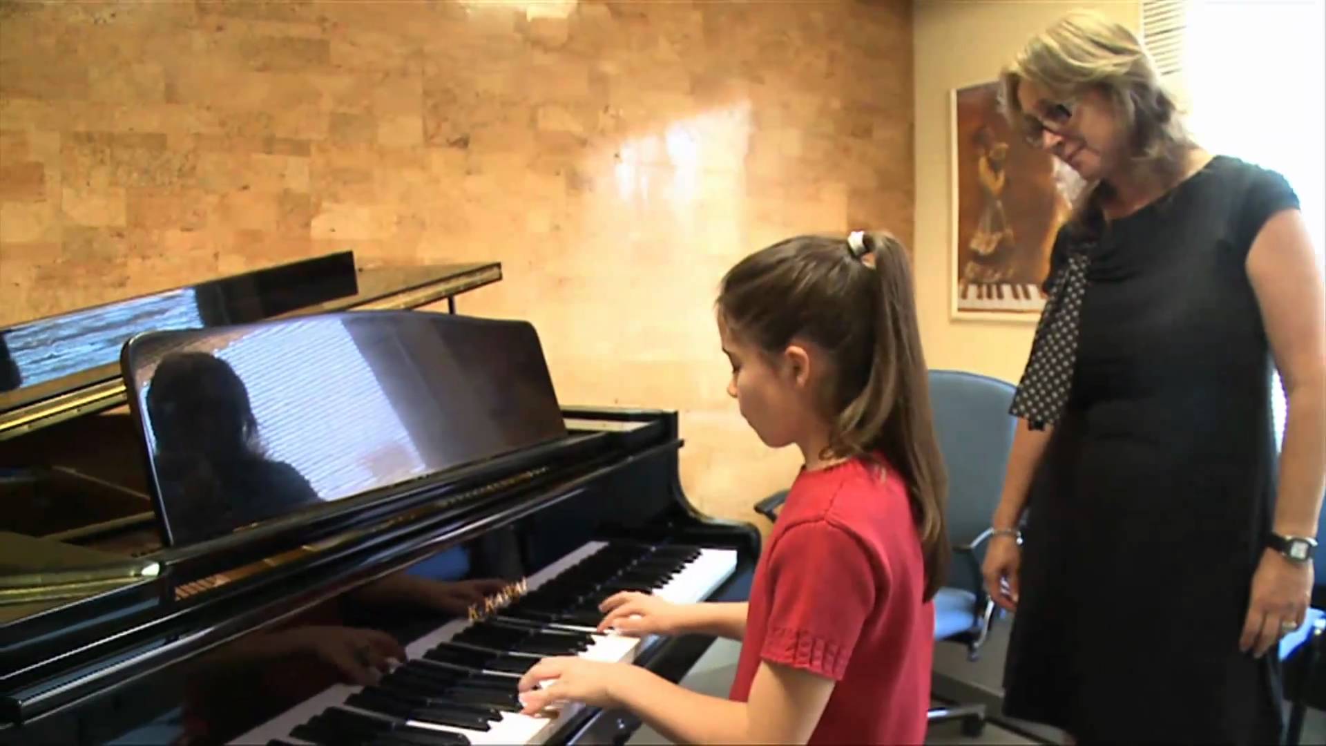 Una alumna de la escuela toca el piano bajo la mirada de su maestra.