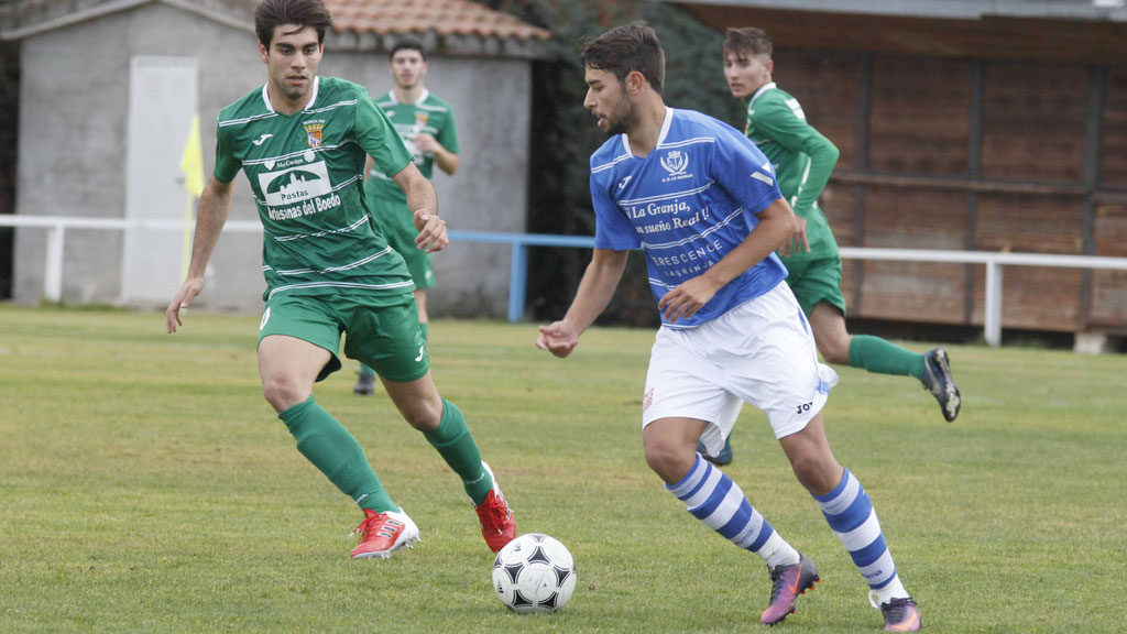 El mediocentro del CD La Granja Juli conduce un balón en el centro del campo ante la presión de un rival. / NEREA LLORENTE