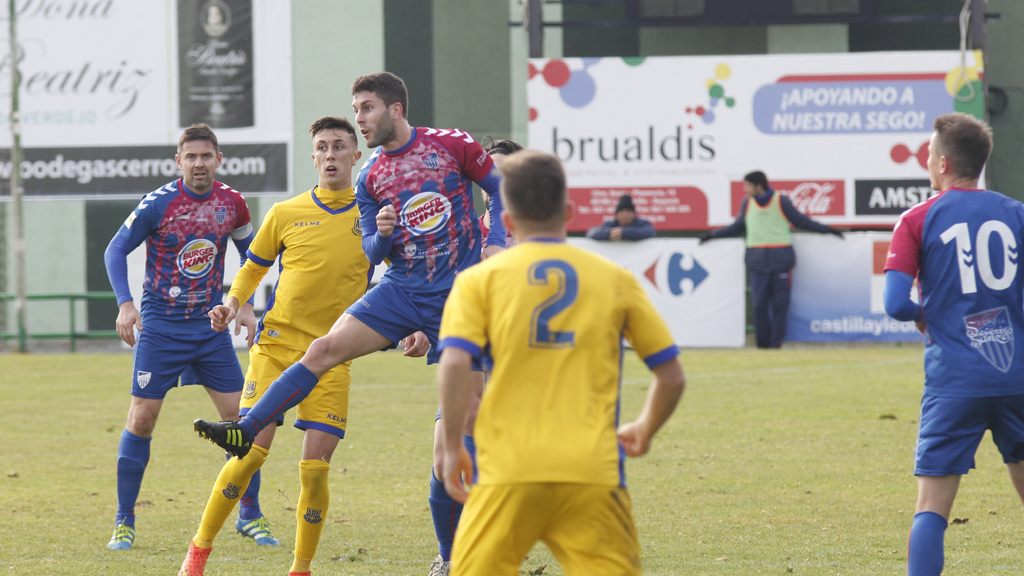 El centrocampista de la Segoviana Manu despeja un balón ante la presión de los jugadores del Alcorcón. / NEREA LLORENTE