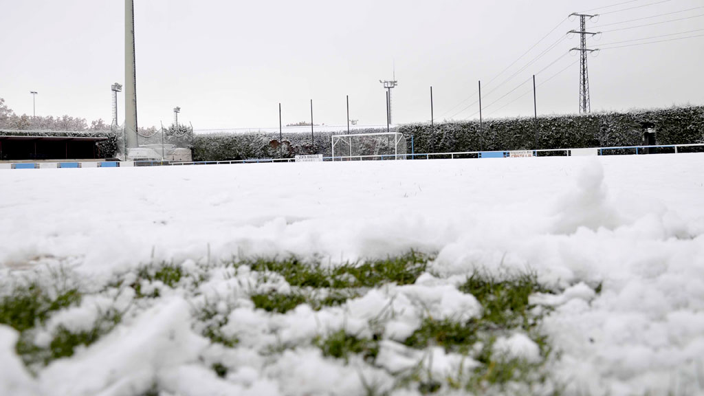 Vista a ras de césped del terreno de juego del campo de El Hospital cubierto de nieve./ JUAN MARTÍN