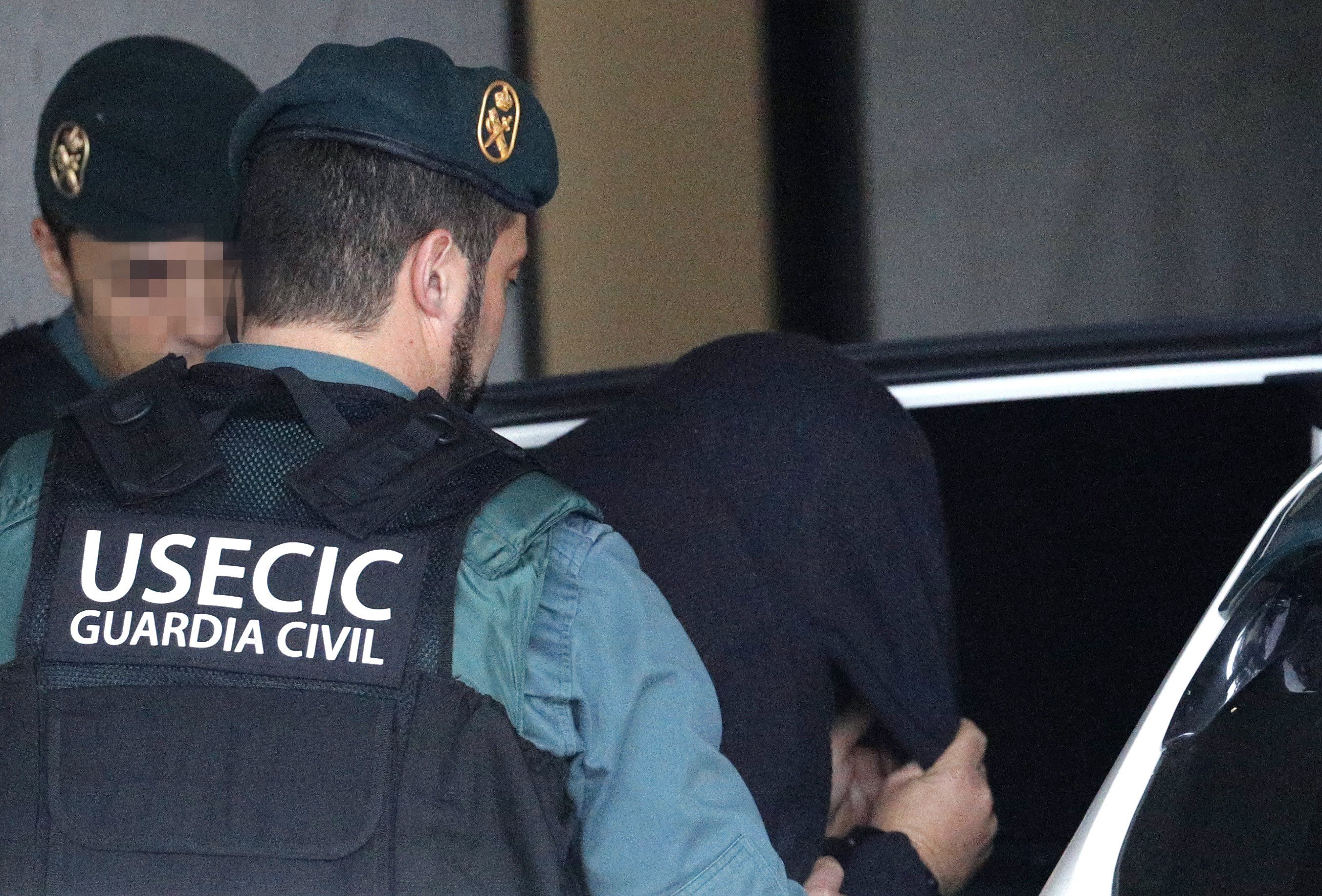 ‘El Chicle’ abandona las dependencias judiciales cubierto por una capucha y custodiado por la Guardia Civil.