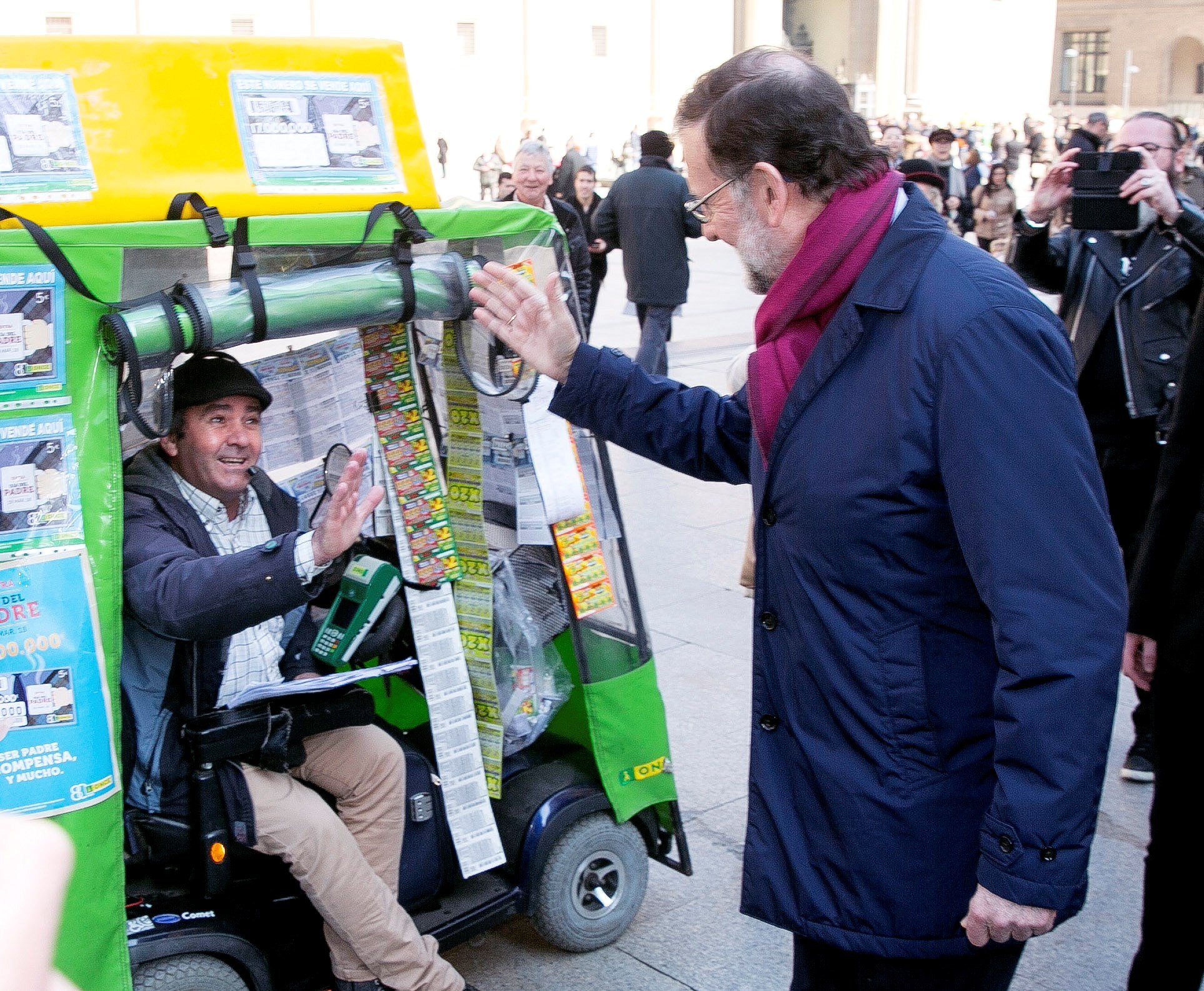 El presidente del Gobierno, Mariano Rajoy, saluda a un vendedor de lotería en la Plaza del Pilar de Zaragoza.